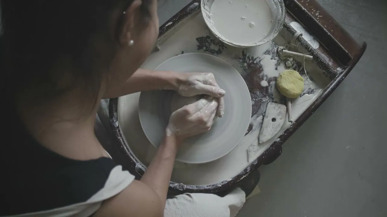 Manos dando forma a una pieza en el torno de cerámica (video de muestra)
